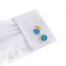 The St Philip Neri Cufflink with light blue enamel and golden stars on a gleaming gold base, displayed on a white shirt. Limited edition.
